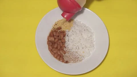 Rice and bean on a white dish being accompanied with "uarini" flour. Stock Footage 137679277