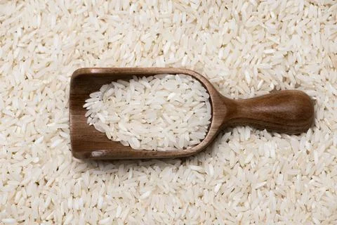 Rice background with pattern. Rice in wooden scoop. Rice closeup with grain.  Stock Photos