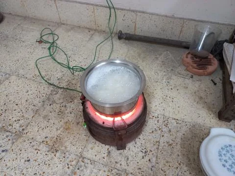 Rice is being cooked in a small pot with an electric heater. Stock Photos