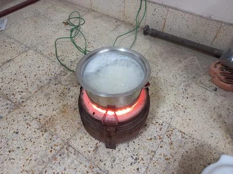 Rice is being cooked in a small pot with an electric heater. Stock Photos