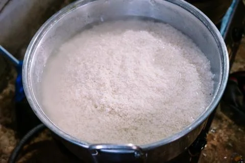 Rice being manually cooked in a large pot. It's currently 60% cooked, showc.. Stock Photos