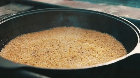 Rice is cooked in cauldron on fire. Step... | Stock Video | Pond5