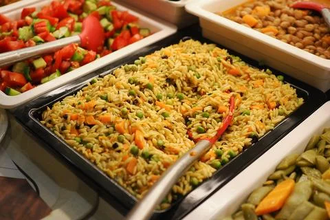 Rice dish served with vegetables in a buffet setting at a dining area Stock Photos