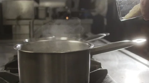 Rice falls into pot of boiling water. Slow motion video Stock Footage 124685717