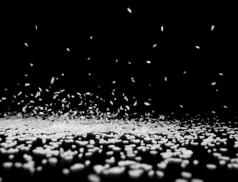 Rice grains fall on a black surface on a black background . Stock Photos