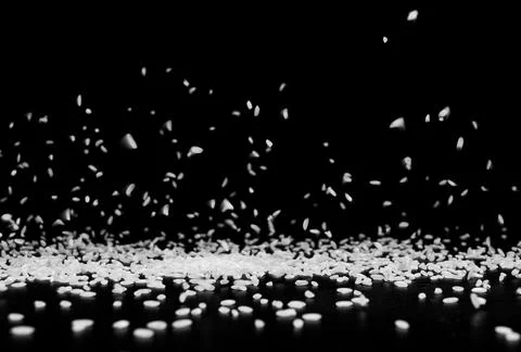 Rice grains fall on a black surface on a black background . Stock Photos