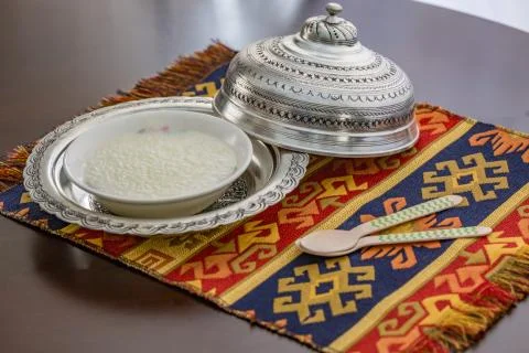 Rice pudding (sutlac) in copper plate with wooden spoons. Stock Photos