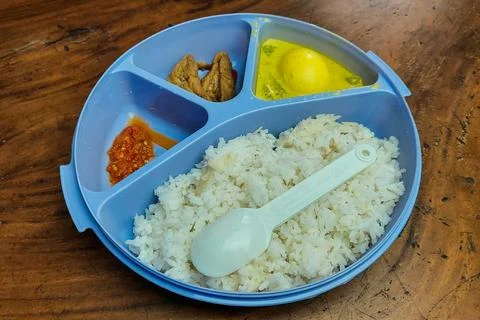 Rice side dishes in a blue Tupperware lunch box on the table Фото