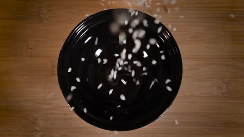 Rice on top rolls onto a black plate Stock Footage 124275067