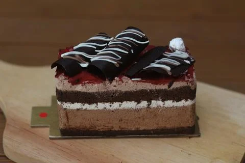 Rich chocolate cake with multiple layers topped with red glaze, white cream,  库存照片