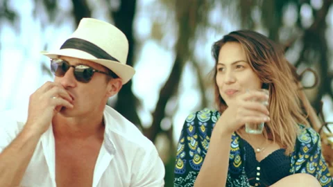 Rich man in white fedora hat hangs out at picnic with millennial friends on sand Stock Footage 199455728