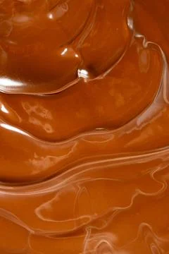 Rich melted chocolate flow background with glossy waves macro view Stock Photos