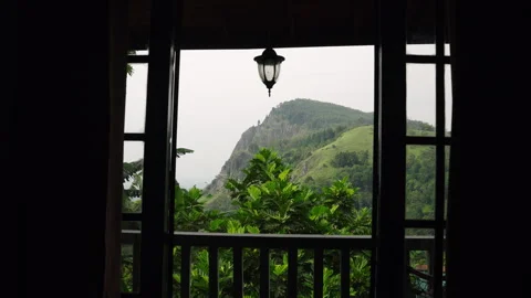 Rich plants frames Ella Rock, viewed from terrace in Sri Lanka. Mist hovers over Stock Footage 274433279