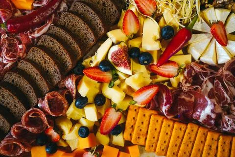 Rich table with different kind of snacks of cold meats bread cheese and fruits Stock Photos