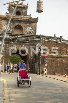 Rickshaw driver at gates of Citadel of Hue Vietnam Stock Photos