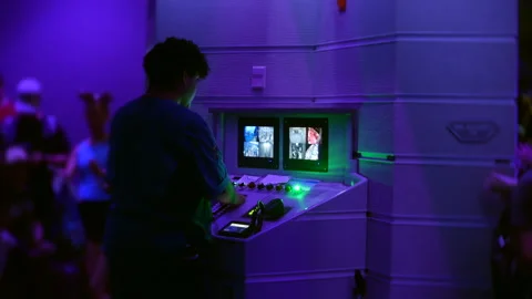 Ride operator at control console, purple-lit theme park interior, surveillance Video stock 336597841