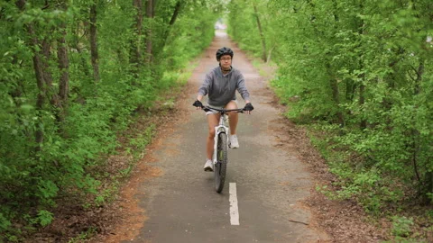 Rider Approaching Camera On Shaded Forest Lane, Focused Expression, Steady Stock Footage 323525765