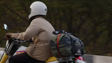 A rider in a beige jacket sets off on an adventure with bundles, riding classic Stock Footage 248076684