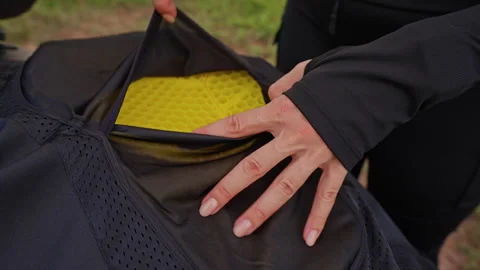 Rider Inserts Yellow Impact Armor Pad Into Black Motorcycle Jacket on a Parked B Stock Footage 340638540