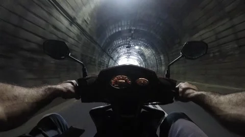 Rider navigating through a dimly lit tunnel on a scooter, journey and freedom Video stock 318951823