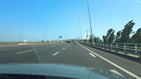 Riders and drivers make their way across the Vasco da Gama Bridge on a sunny day Stock Footage 284331149