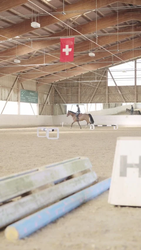 Riders training with their horses on a show jumping course inside a large riding 스톡 동영상 333697948