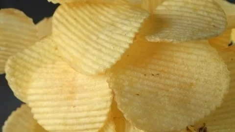 Ridged potato chips falling in slow motion on black background Stock Footage 345451165