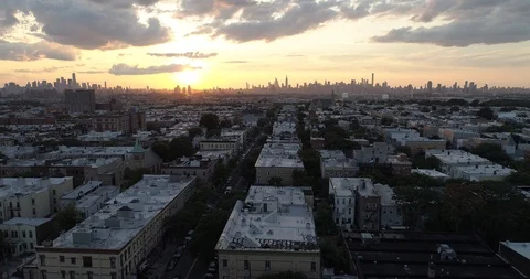 Ridgewood rooftops face the Manhattan skyline beneath a vivid sunset Stock Footage 93047104