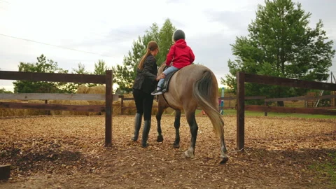 Riding coach is training future champion in pony club, little boy is riding Stock Footage 213579086