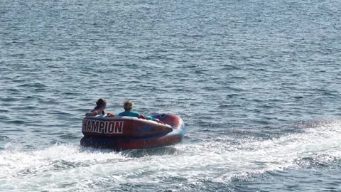 Riding an inflatable donut behind a fast boat Stock Footage 315878932