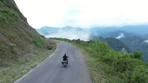 Riding motorbike on mountainside amongst clouds and winding roads in India. Stock Footage