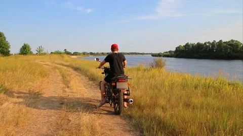 Riding a motorcycle parallel to the river in search of a new route Video stock 111520194