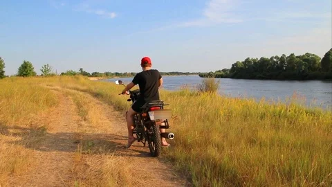 Riding a motorcycle parallel to the river in search of a new route Video stock 112264843