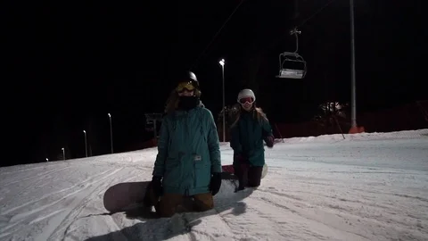 Riding at the night on the ski resort. Two female snowboarder are standing on Video stock 121425822