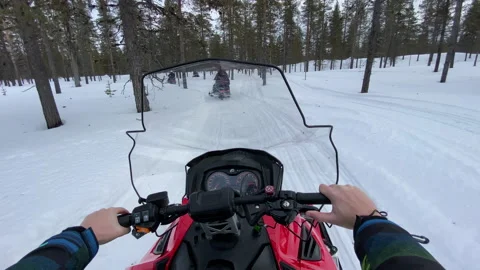 Riding a red snowmobile in winter in a forest in Lapland, Finland. Stockbeeldmateriaal 149396799