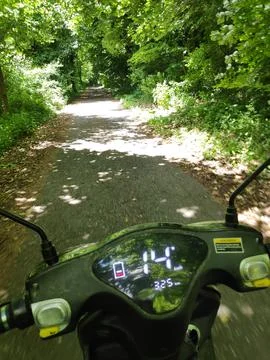Riding a Scooter Along a Forest Path 스톡 사진
