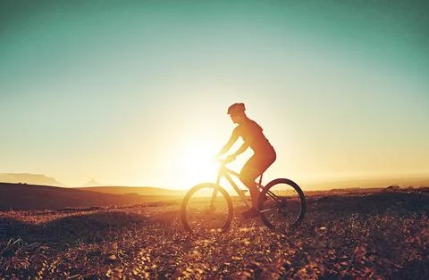 Riding off into the sunset. an adventurous mountain biker out for a ride in the Stock Photos