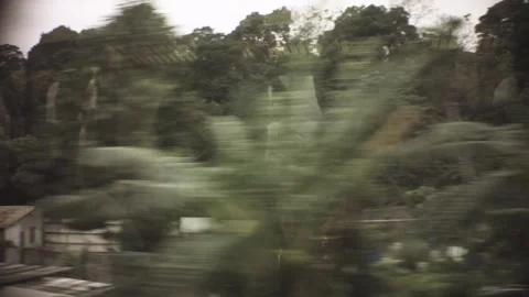 Riding on train view of old dirty poorly build small factory structure with gras Stock Footage 237251719