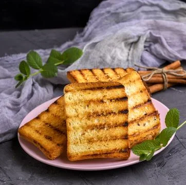 Ried square pieces of white bread on a pink ceramic plate Stock Photos
