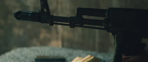 Rifle fires outdoors as muzzle flash bursts from barrel above ground mat with Stock Footage 310414349