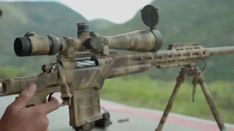 A Rifle set up at a gun range, as a man pulls the trigger and fire a round as Stock Footage 332957957