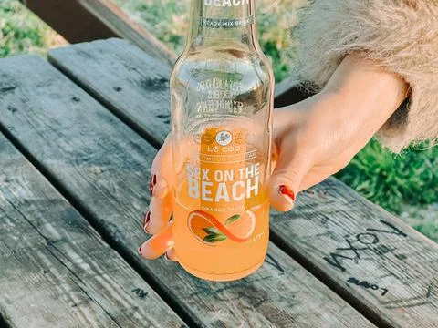 Riga, Latvia -May 1, 2026: Hand Holding Bottled Orange Cocktail Drink Outdoor Stock Photos