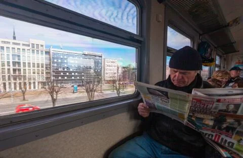 Riga, Latvia - May 7, 2017: Passenger reads the newspaper in train are on the Stock Photos