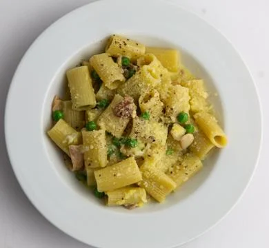 Rigatoni carbonara with peas on white plate classic italian pasta dish Stock Photos