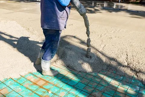 Rigger, worker is holding pump hose to pouring fresh concrete into building.. Stock Photos