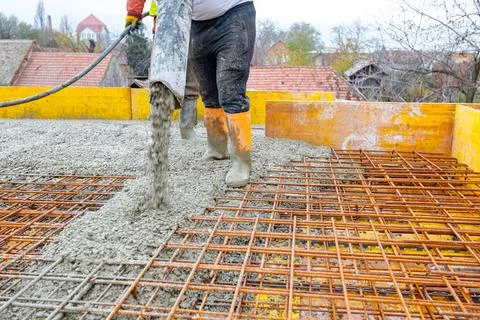 Rigger, worker is holding pump hose to pouring fresh concrete into building.. Stock Photos