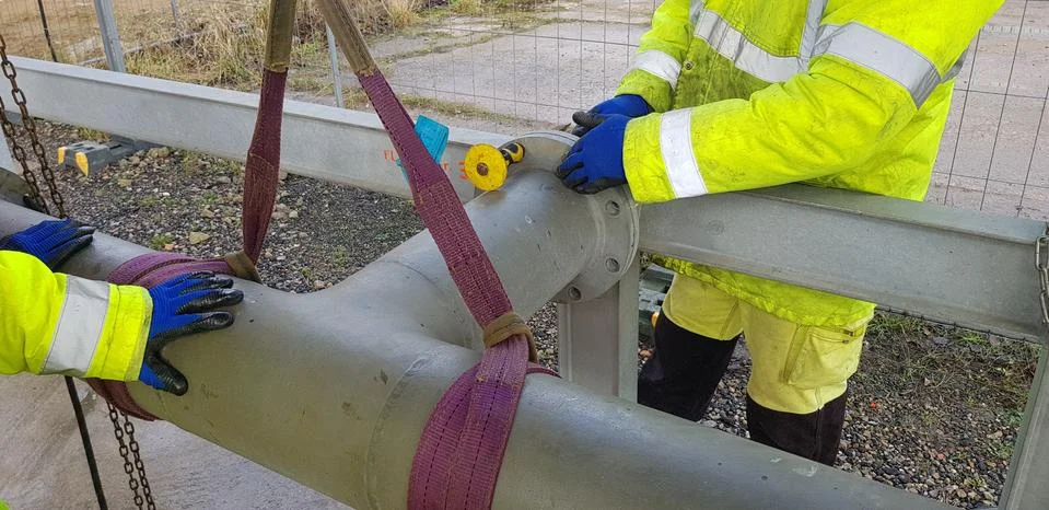Riggers move the pipe using two chain blocks Stock Photos