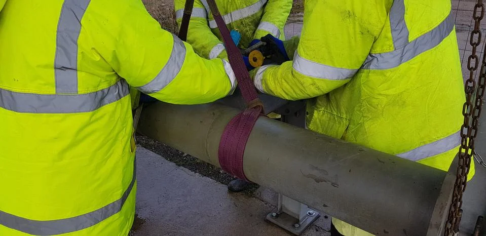 Riggers move the pipe using two chain blocks Stock Photos