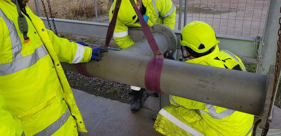 Riggers move the pipe using two chain blocks Stock Photos