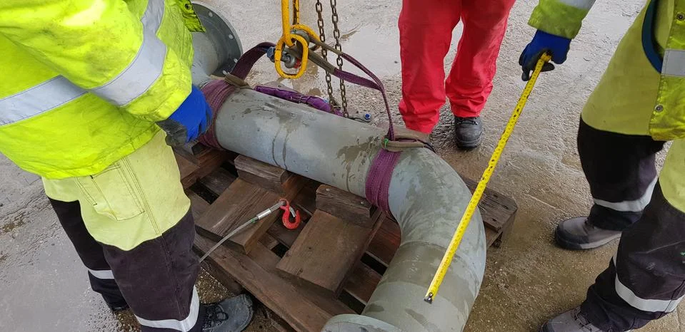 Riggers move the pipe using two chain blocks Stock Photos
